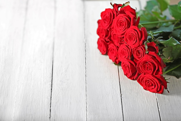 Beautiful bouquet of red roses on wooden background