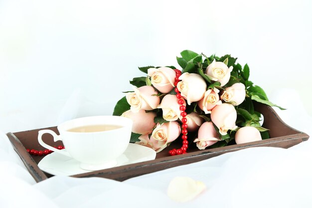 Beautiful bouquet of roses, on wooden tray, on light background