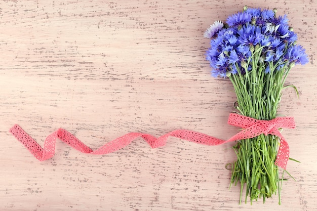 Beautiful bouquet with lace ribbon on wooden background