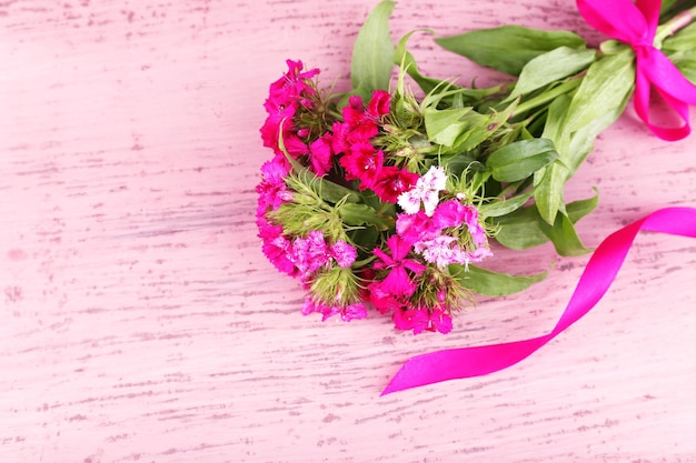 Beautiful bouquet with ribbon on wooden background