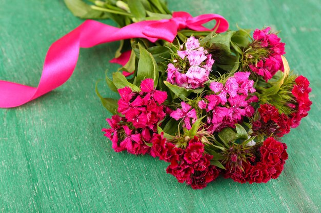 Beautiful bouquet with ribbon on wooden background