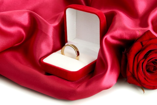 Beautiful box with wedding ring and rose on red silk background