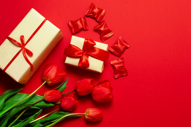 Красивые коробки, завернутые в бумагу и красную ленточку, цветы тюльпанов и конфеты