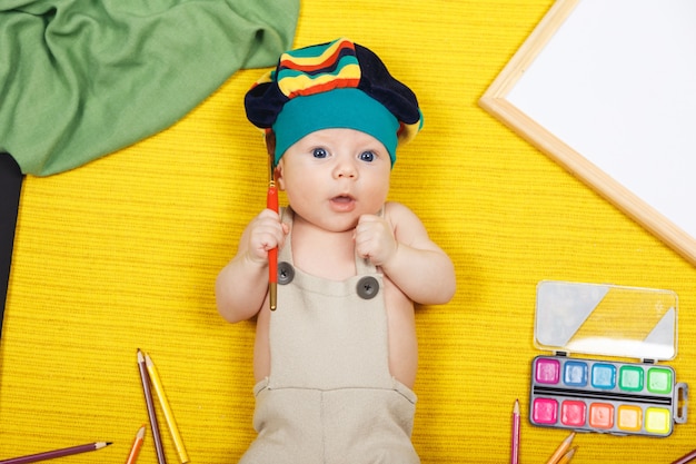 Photo beautiful boy lie on the floor and draw with pencils. works of child