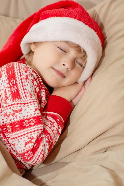 a beautiful boy in New Year's pajamas and a Santa hat is lying in bed