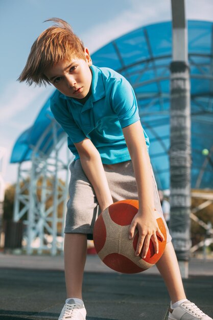Photo a beautiful boy in a sports uniform caught a basketball a boy holds a ball in his hands