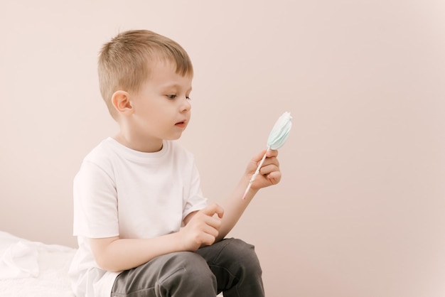 Photo a beautiful boy with a meringue in his hands on a light background