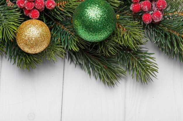 Beautiful branches of a Christmas tree with cones and toys on a white wooden background with the inscription Merry Christmas