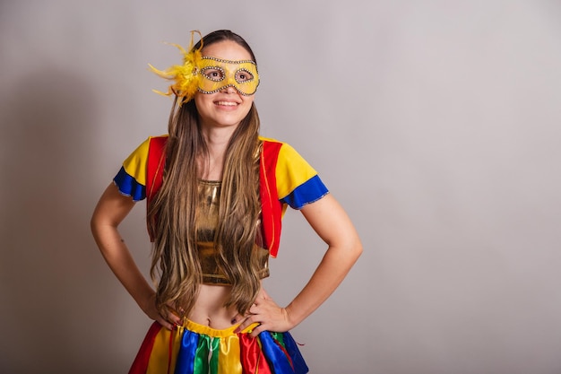 Beautiful brazilian caucasian woman wearing frevo carnival\
clothes wearing a mask hands on hips