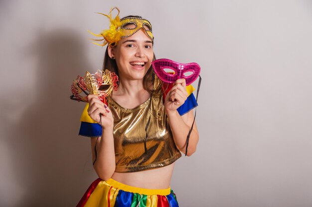 Beautiful brazilian caucasian woman wearing frevo carnival
clothes wearing a mask holding carnival masks