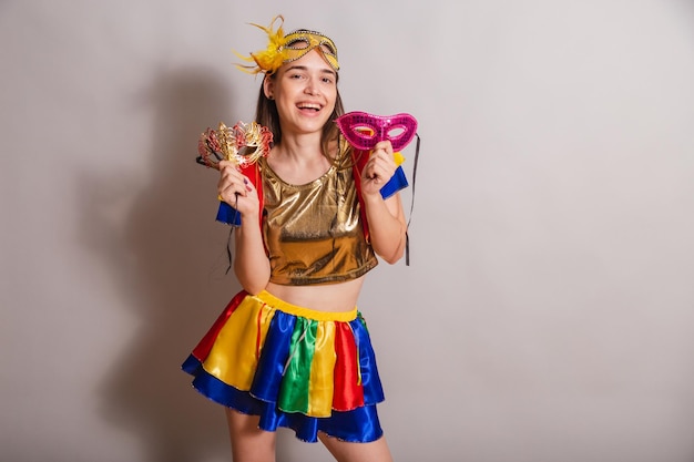 Beautiful brazilian caucasian woman wearing frevo carnival\
clothes wearing a mask holding carnival masks