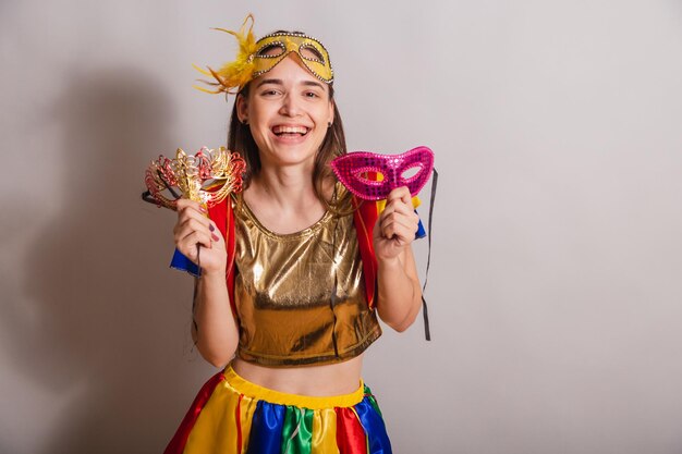 Beautiful brazilian caucasian woman wearing frevo carnival\
clothes wearing a mask holding carnival masks