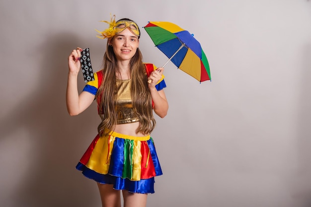 Beautiful brazilian caucasian woman wearing frevo carnival
clothes wearing a mask holding condom prevention