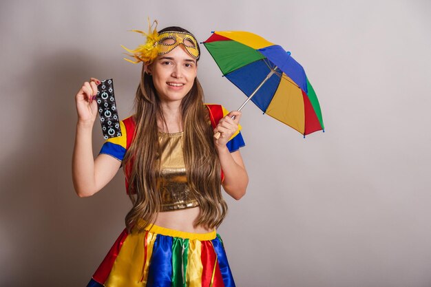 Beautiful brazilian caucasian woman wearing frevo carnival\
clothes wearing a mask holding condom prevention