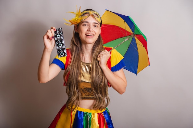 Bella donna caucasica brasiliana che indossa abiti da carnevale frevo indossando una maschera che tiene il preservativo prevenzione