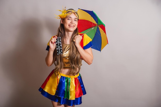 Beautiful brazilian caucasian woman wearing frevo carnival\
clothes wearing a mask holding condom prevention