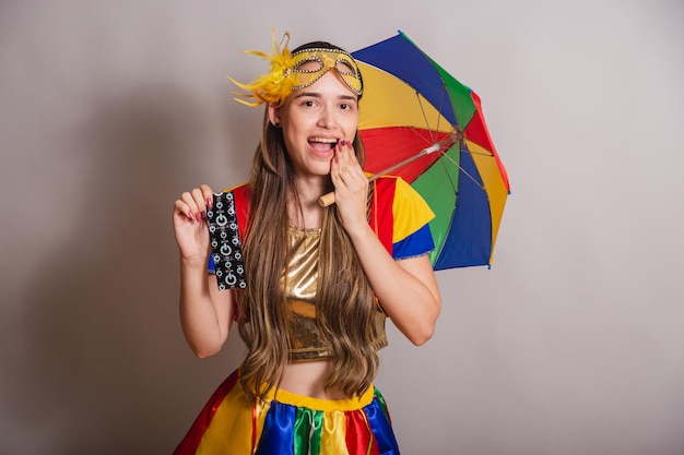 Beautiful brazilian caucasian woman wearing frevo carnival\
clothes wearing a mask holding condom prevention