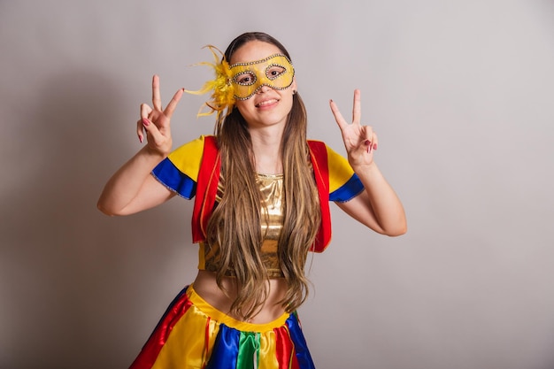 Beautiful brazilian caucasian woman wearing frevo carnival\
clothes wearing a mask peace and love