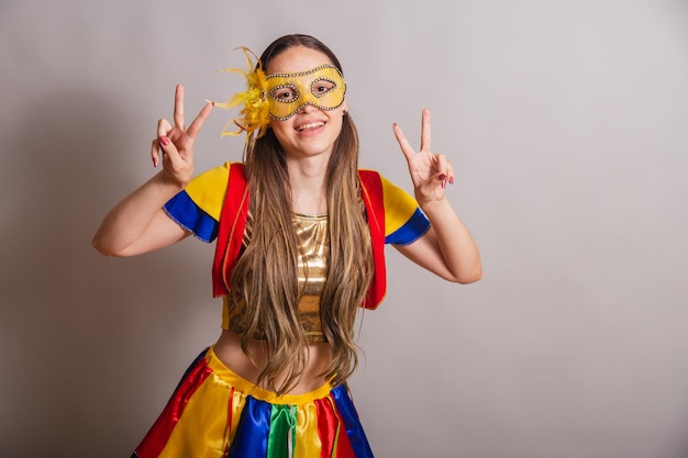 Beautiful brazilian caucasian woman wearing frevo carnival\
clothes wearing a mask peace and love