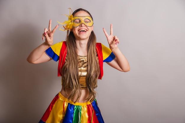 Beautiful brazilian caucasian woman wearing frevo carnival
clothes wearing a mask peace and love