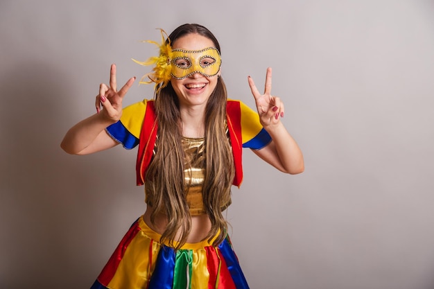 Beautiful brazilian caucasian woman wearing frevo carnival
clothes wearing a mask peace and love