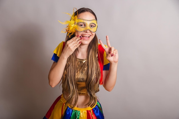 Beautiful brazilian caucasian woman wearing frevo carnival\
clothes wearing a mask peace and love