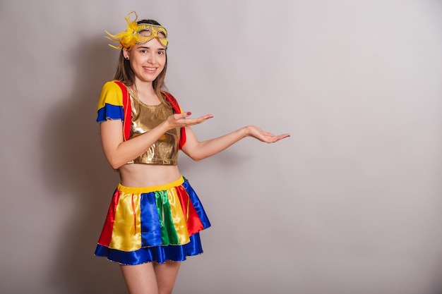 Beautiful brazilian caucasian woman wearing frevo carnival\
clothes wearing a mask showing something to the right