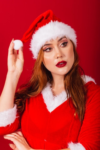 クリスマスの服を着た美しいブラジルの赤髪の女性サンタ クロース カメラの顔モデリングの垂直クローズ アップ ショット