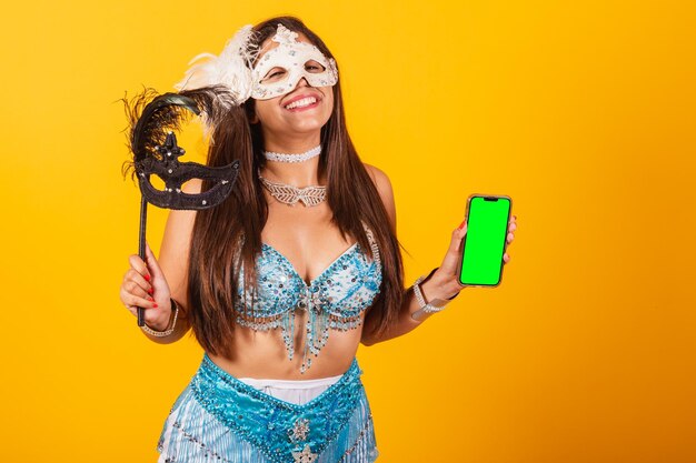 Beautiful brazilian woman in blue and white carnival clothes holding mascara and smartphone