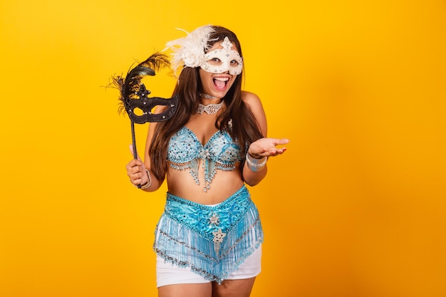 Beautiful brazilian woman in blue and white carnival clothes holding mask inviting