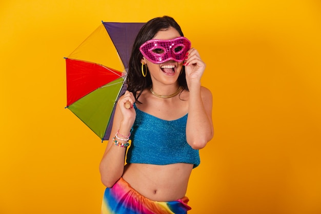 カラフルな傘とカーニバル マスクを保持しているカーニバルの服で美しいブラジル人女性