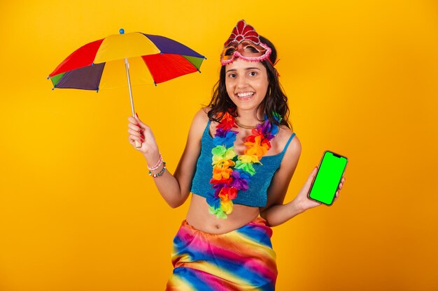 Beautiful brazilian woman in carnival clothes holding smartphone with green screen