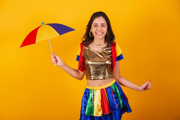 Beautiful brazilian woman in carnival clothes with frevo clothes and colorful umbrella dancing