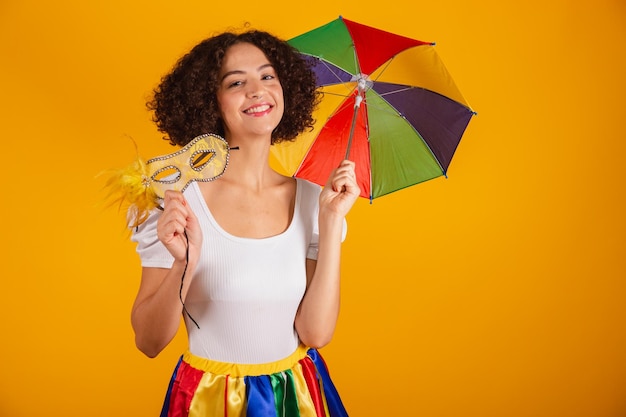 Beautiful Brazilian woman dressed in carnival clothes colorful skirt and white shirt frevo umbrella holding carnival mask