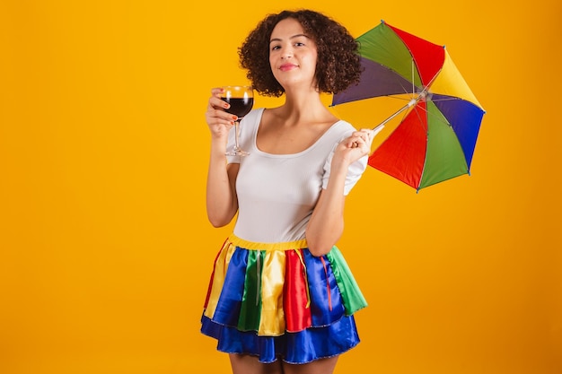 Beautiful brazilian woman dressed in carnival clothes colorful skirt and white shirt frevo umbrella holding glass of wine