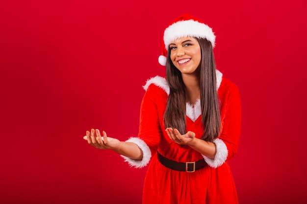 クリスマスの服を着た美しいブラジル人女性サンタクロースが手を誘う