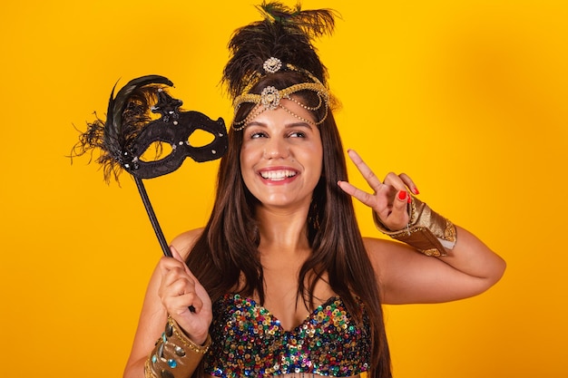 Beautiful brazilian woman in golden carnival clothes holding carnival mask unbelievable