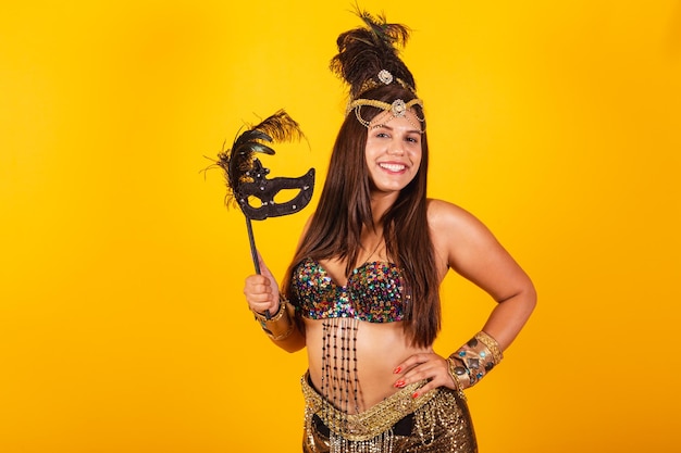 カーニバル マスクを保持している黄金のカーニバルの服で美しいブラジル人女性