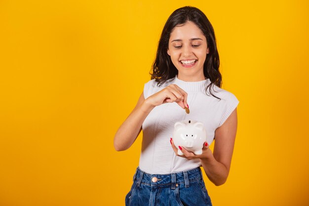 貯金箱とコインを保持している美しいブラジル人女性