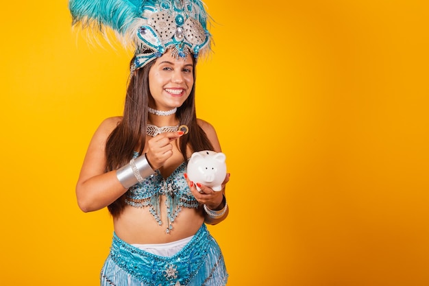 Beautiful brazilian woman with blue carnival clothes feather crown carnival queen holding piggy bank and coin