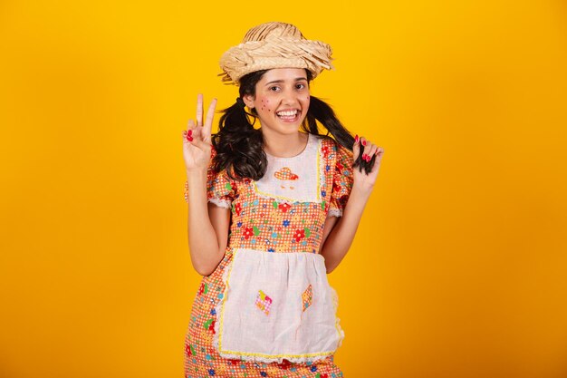 Beautiful brazilian woman with festa junina clothes sign of peace and love with her fingers