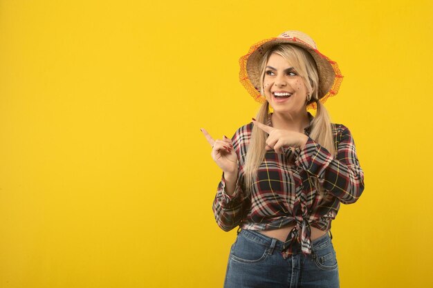 Beautiful brazilian woman with festa junina clothes on yellow background