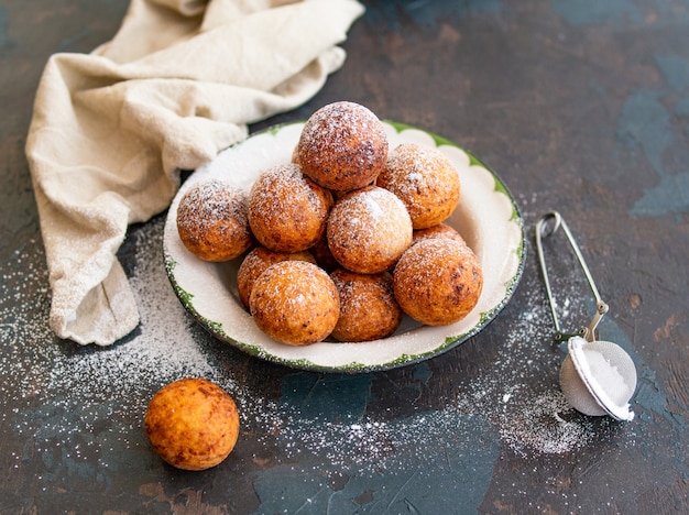 Beautiful breakfast. Cottage cheese donuts balls with sugar powder on a dark background. Close up. Copy space,