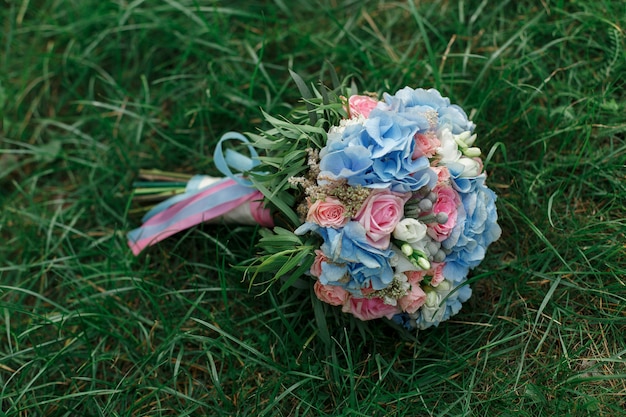 Beautiful bridal bouquet  on green grass in summer day. wedding floral and decor. festive floral arrangement of roses and violets outdoors. wedding day. wedding details.