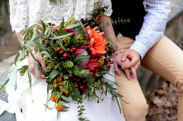 Bellissimo bouquet da sposa in stile rustico nelle mani degli sposi