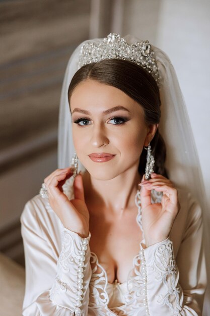 Beautiful bride in a dressing gown in the morning before the wedding ceremony Incredible hairstyle of the bride Natural and modern makeup Portrait of a young bride in a dressing gown