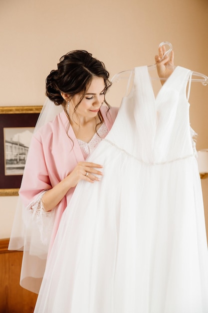 Beautiful bride examines her wedding dress