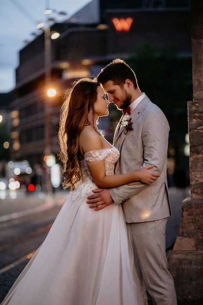 Красивая невеста и жених, обнимая и целуя в день своей свадьбы на открытом воздухе
