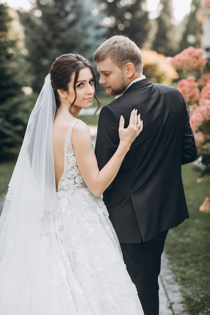 beautiful bride and groom hug each other in a large area, behind them a palace of light color