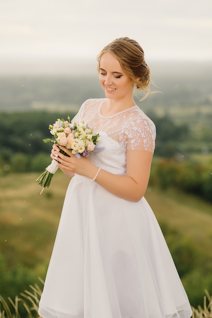 Una bella sposa tiene in mano un bouquet da sposa